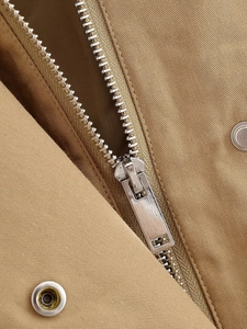 Detailed macro shot of silver metal zipper and button on khaki twill jacket fabric
