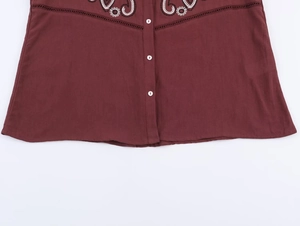 Detailed close-up of wine red embroidered shirt with white floral cutwork and buttons