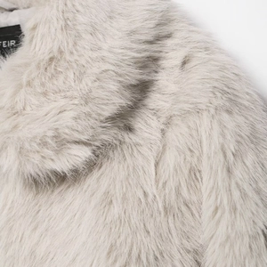 Close-up of stylish faux fur short jacket in light grey showing plush texture and brand label