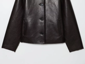 Close-up of faux leather jacket with round buttons, side pockets, and plush shearling lining
