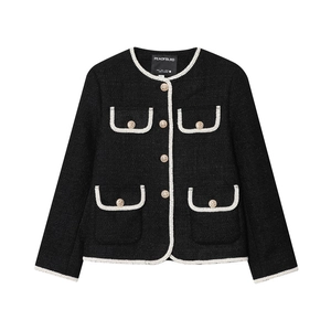 Détail de la veste en tweed noir avec bordure blanche, boutons dorés et texture tissée