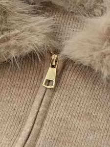 Detail of camel knit top featuring a plush faux fur collar and a golden trapezoid zipper
