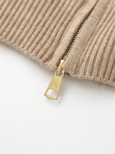 Close-up of golden metal zipper and beige rib-knit sweater texture detail