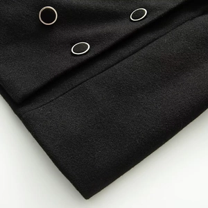 Macro detail of black wool coat featuring decorative silver-ringed buttons and premium texture