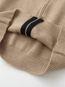 Detail of camel knit cardigan with gold metal zipper and black ribbon trim accent