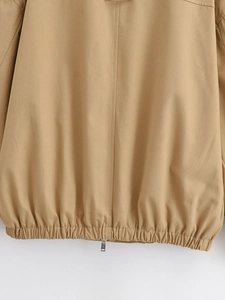 Macro detail of khaki jacket featuring elastic hem texture and silver metal zipper slide
