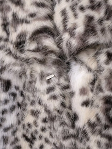 Macro shot of faux fur texture with animal print pattern and a small silver metal logo tag