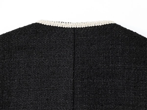 Détail de l'encolure d'une veste en tweed noir avec bordure tissée crème de haute qualité