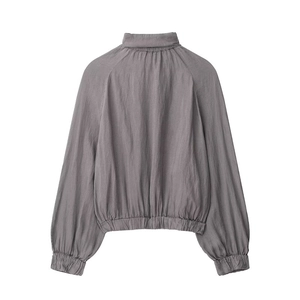 Detail of grey bomber jacket showing elastic stand-up collar and lantern sleeve texture