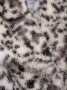 Close-up of leopard print faux fur texture and 'WOMAN' label on fashion jacket collar