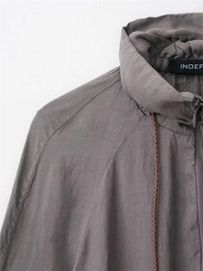 Detail of grey bomber jacket with high stand collar and contrast woven drawstring accents