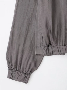Detailed close-up of elastic ruffled cuffs and hem on a gray-brown bomber jacket