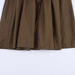 Detailed view of dark brown pleated hem with refined stitching on a long sleeve dress