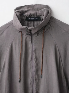 Detail of dark grey pilot jacket showing stand collar, woven drawstrings and zipper