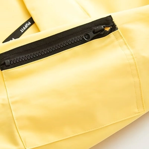 Detail of waterproof yellow jacket featuring a black zipper pocket and a brand woven label