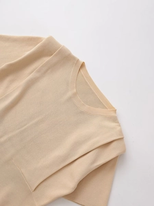 Close-up of the pleated shoulder detail and ribbed crewneck on this apricot knit top