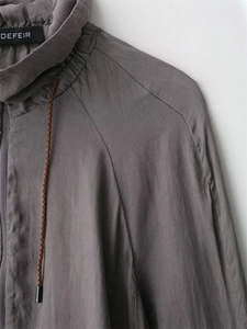 Detail of high stand collar and woven drawstring on dark grey pilot jacket with texture