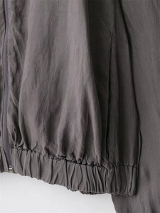 Detail of grey lightweight bomber jacket featuring elastic hem and functional zipper pocket