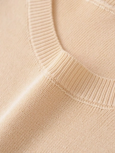 Close-up of ribbed crewneck and high-density knit texture on a beige sweater