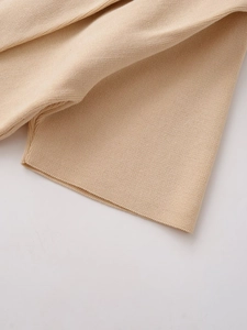 Close-up of beige knit fabric showing fine texture and high-quality hem stitching