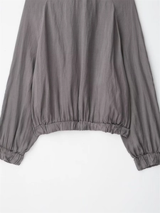 Detail of dark grey bomber jacket featuring elasticated hem and textured fabric finish