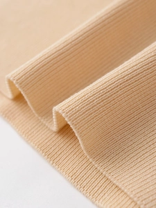 Detailed macro view of the premium beige ribbed knit texture on this women's top