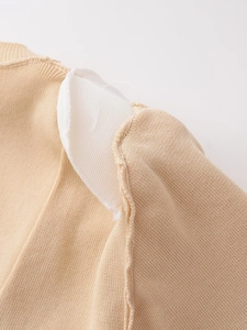 Detail view of the interior padded shoulder construction on the beige knitted top