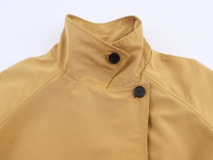 Detail shot of a ginger short trench coat showing overlapping stand collar and black buttons