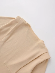 Close-up of beige knit top showing fine texture and ribbed neckline detail