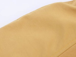 Close-up of yellow trench coat fabric showing fine weave texture and neat stitching