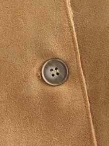 Detail of a brown marble-textured button and neat stitching on faux leather jacket
