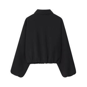 Detail of a black cropped jacket featuring puff sleeves and elasticated hemline texture