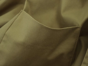Close-up of olive green jacket detail showing precise double-needle stitching on pockets