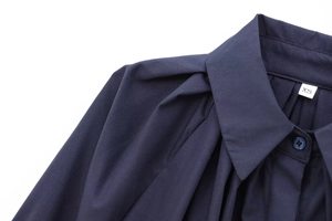 Détail du col d'une chemise en popeline bleu marine avec plis et étiquette de taille