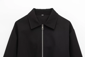 Close-up of black zipper jacket showing silver metal zip and textured woven fabric