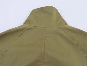 Detail of olive jacket showing raglan sleeves, stand collar and double-stitched seams