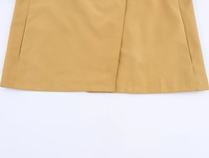 Detailed view of the ginger yellow trench coat hem featuring precise stitching and texture