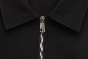 Detailed close-up of a black jacket collar with a premium silver metal zipper and stitching