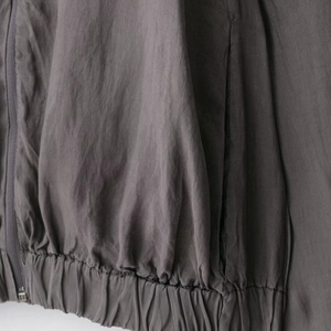 Close-up of lightweight dark grey pilot jacket featuring zip closure and elastic hem