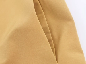 Macro detail of camel trench coat twill fabric showing high-quality stitching and texture