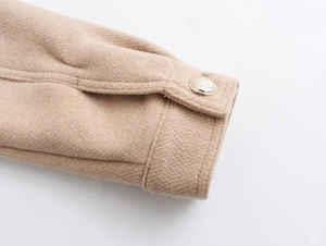 Close-up of camel wool coat cuff with detailed gold metal button and fine stitching