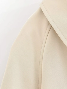 Detailed macro view of the shoulder seams and fine stitching on a beige trench coat jacket