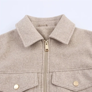 Detail showing the collared neckline with golden snap buttons and a metal zipper closure