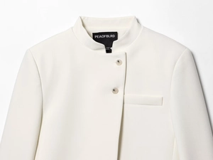 Détail du col montant et de la fermeture asymétrique à boutons sur le blazer blanc cintré
