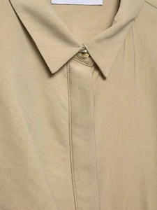 Detail of khaki blouse collar featuring fine fabric texture and a gold dome button