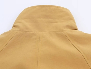 Macro detail of mustard yellow jacket showing stand collar and double-stitched seams
