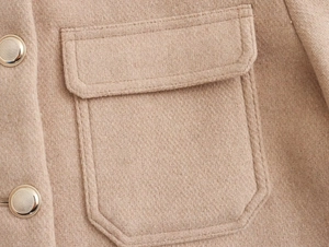 Detail view of khaki wool jacket featuring flap pocket and golden metal buttons