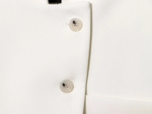 Gros plan des boutons en marbre et du tissu tissé sur un blazer blanc cintré