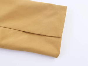 Detailed close-up showing the camel woven fabric texture and hem of the trench coat