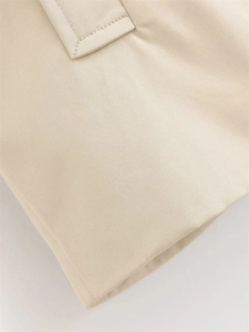 Detail of clean stitching on the beige twill fabric hem of the short trench coat